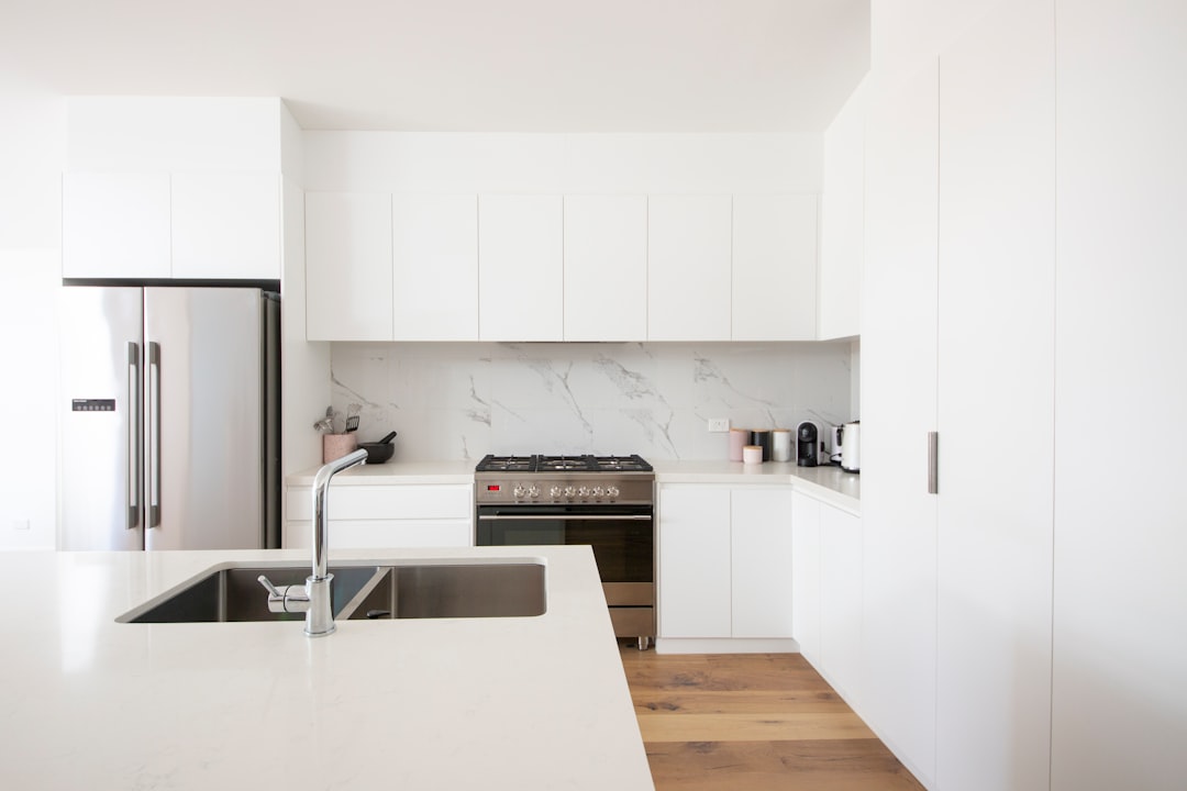 Minimalist kitchen with white cabinets, marble backsplash, and stainless steel appliances